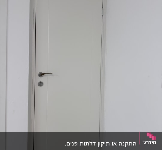 דלת לבנה עם ידית כסופה בקיר לבן
